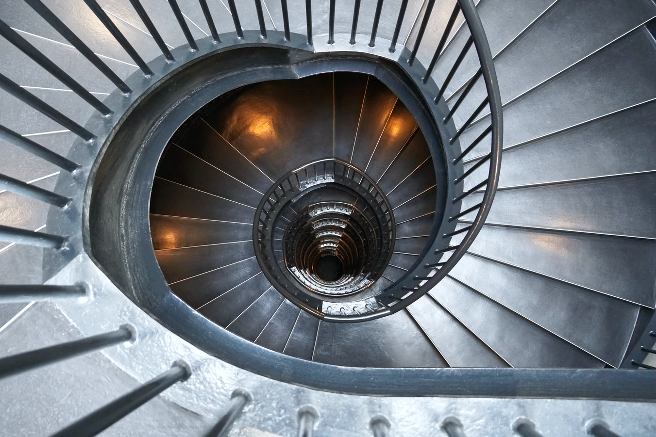 A seemingly endless spiral staircase as seen from above. Looking like an endless hole.